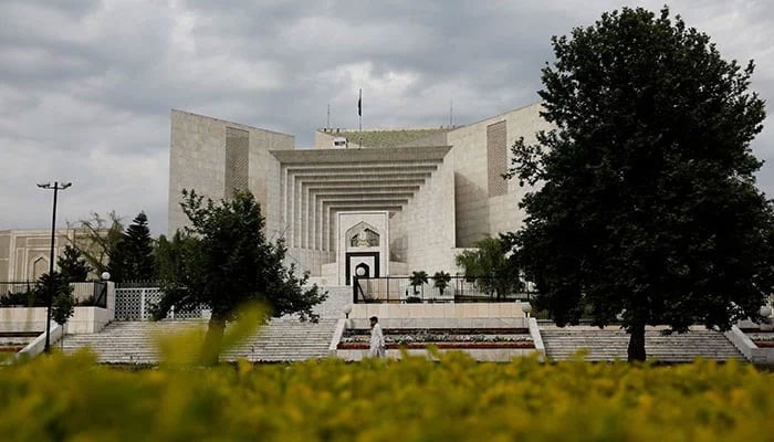 A man uses his mobile phone as he walks past the Supreme Court of Pakistan building in Islamabad on May 13, 2023. — AFP