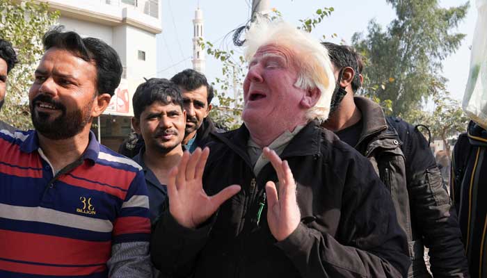 Saleem Bagga, seen by some as a lookalike of US President-elect Donald Trump, poses for a selfie with a customer while selling kheer, a traditional South Asian rice pudding, along a road in Sahiwal, Pakistan January 13, 2025. — Reuters