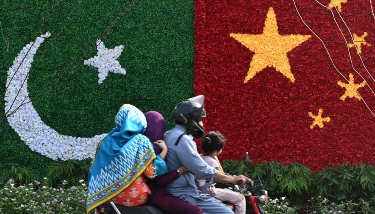 A family passes by a floral display of Pakistan and China flags. — AFP/File