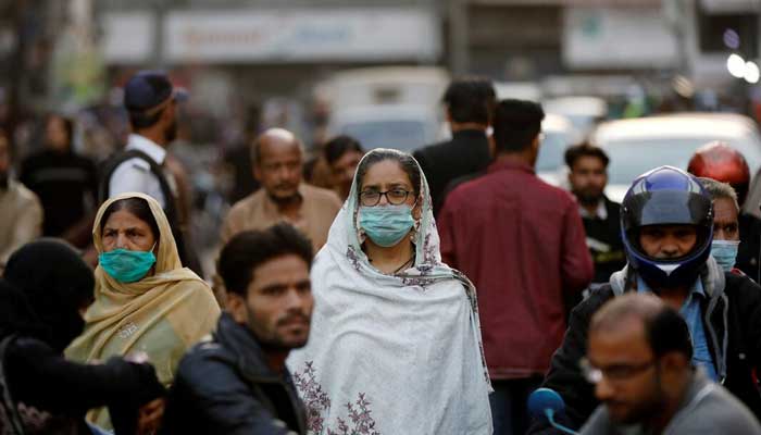 Women wear protective masks as they walk through a crowd along a market in Karachi, on December 2, 2020. — Reuters