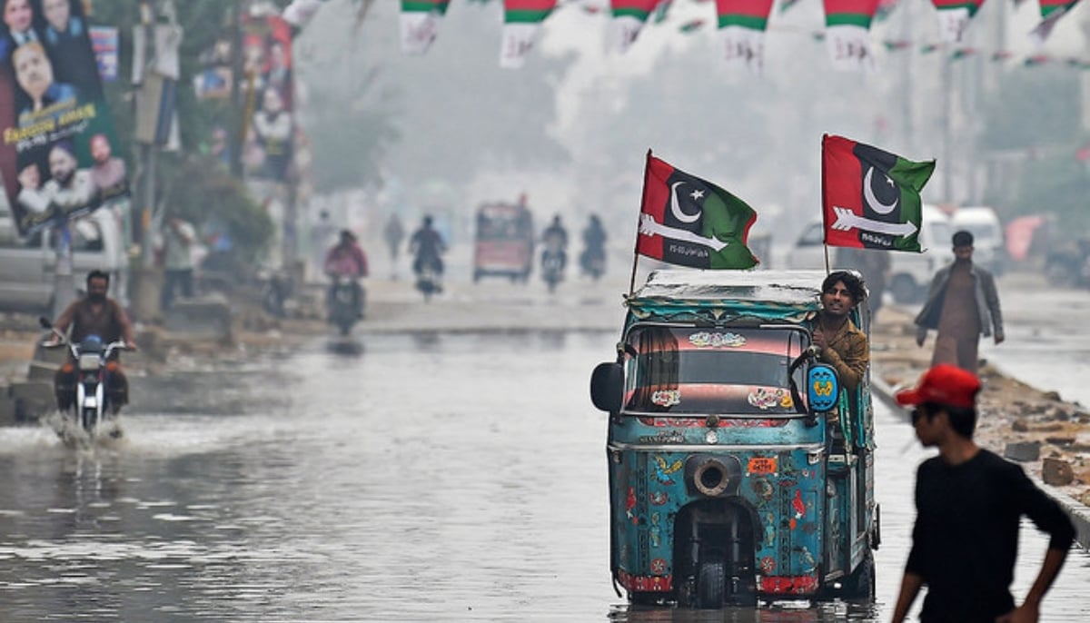 An auto rickshaw with Pakistan Peoples Party (PPP) flags make its way through a flooded street in Karachi on February 4, 2024. — AFP