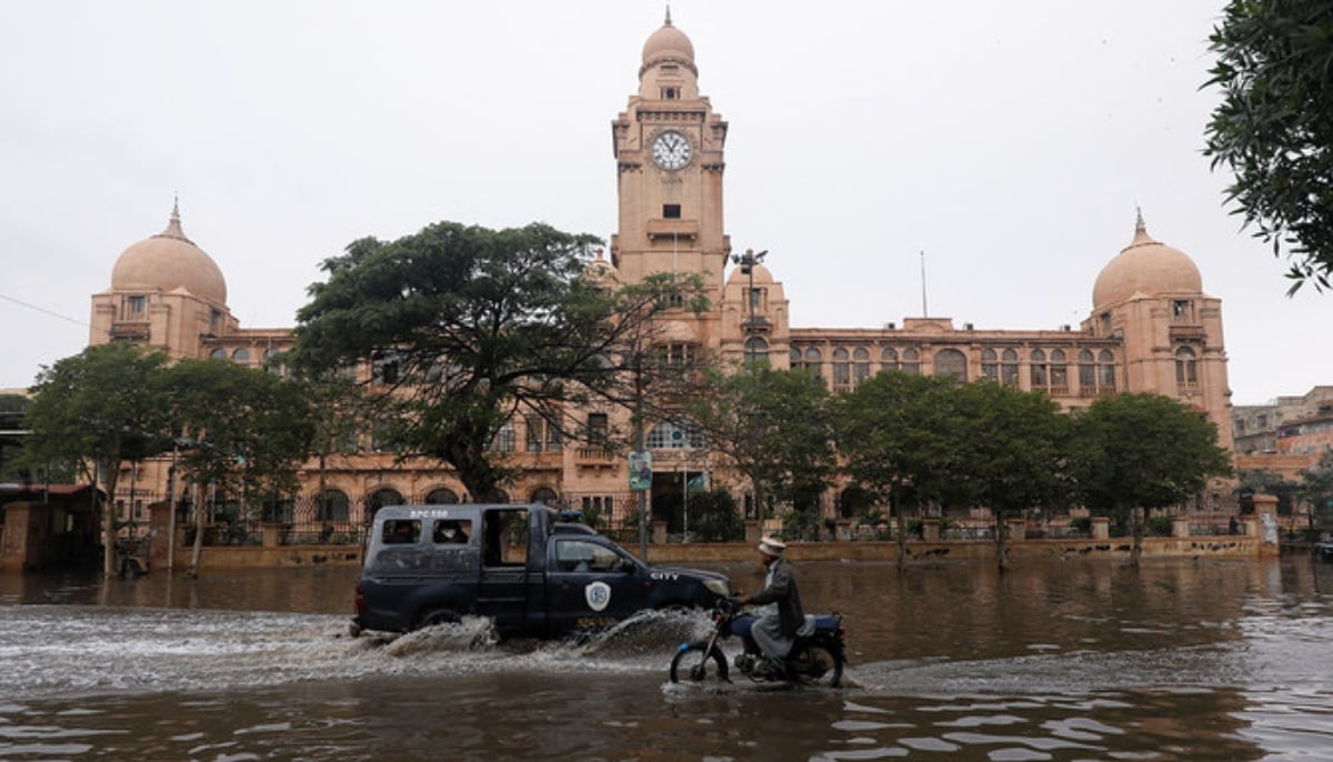 Vehicles drive through a flooded road in front of the colonial-era building of the Karachi Municipal Corporation (KMC), after a thunderstorm in Karachi on February 4, 2024. — AFP