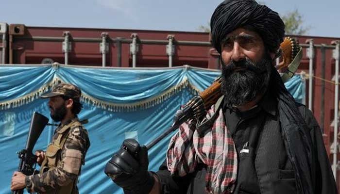 Taliban fighters stand guard while people wait to receive sacks of rice, as part of humanitarian aid sent by China, at a distribution centre in Kabul, Afghanistan, April 7, 2022. — Reuters