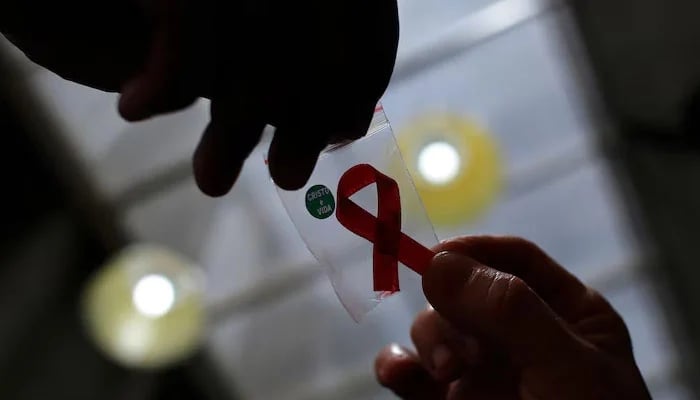 An representational image shows a nurse (left) handing out a red ribbon to a woman, to mark World Aids Day, at the entrance of Emilio Ribas Hospital, in Sao Paulo on December 1, 2014. — Reuters