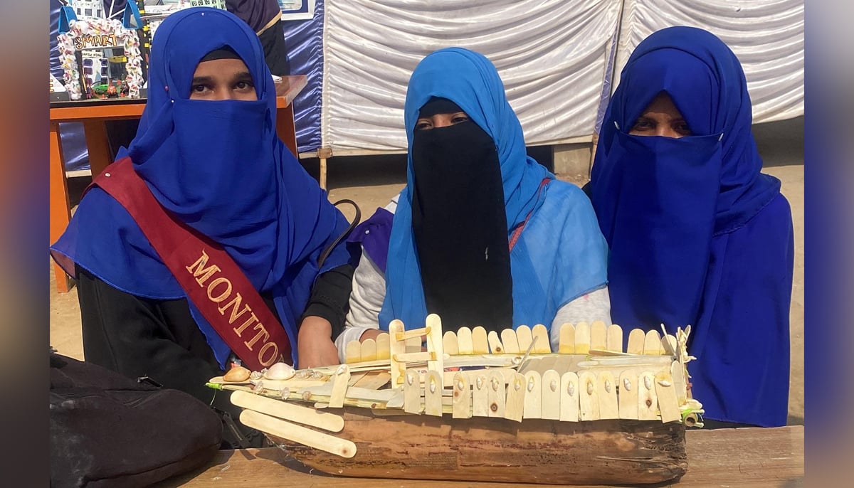 Dua (left), Kausar and Mehak present a boat made from a banana tree trunk and ice lolly sticks at the Tando Allahyar STEAM Muqablo. — Photo via author