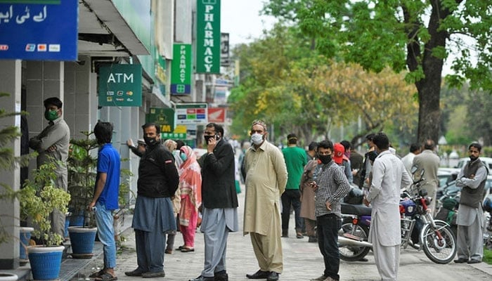 People wait for their turn outside an ATM in Islamabad. — AFP/File