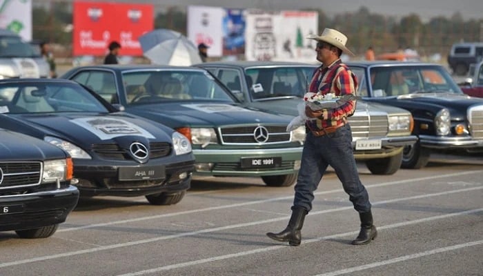 A Pakistani participant walks past vintage cars at the end of the Pakistan Motor Rally in Islamabad. — AFP/File