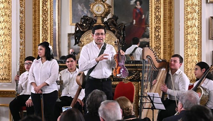 Argentinian musician and director Favio Chavez explains to the audience that the violin he is holding is made from discarded paint cans as members of the Paraguayan Recycled Orchestra of Cateura perform for an audience inside Lancaster House in London on January 26, 2025. — AFP