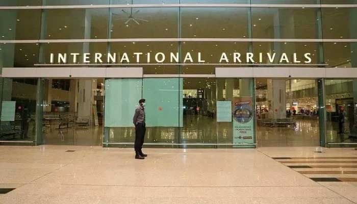 Airport Security Force (ASF) personnel wearing a mask stand guard at the international arrivals area at Islamabad Airport. — X/@mophrd