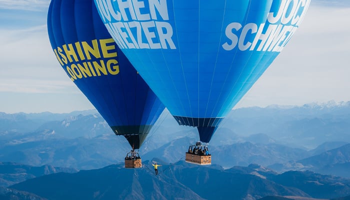 The two hot air balloons at 8,202 feet in the sky pictured with a man strolling the suspended slackline. — Guinness World Records/File