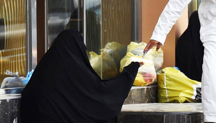 A person hands out cash to a roadside beggar. — AFP/File