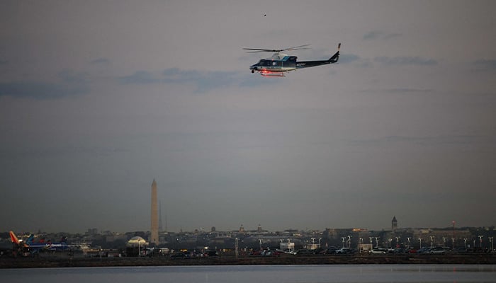 A helicopter flies near the crash site of the American Airlines plane on the Potomac River after the plane crashed on approach to Reagan National Airport on January 30, 2025 in Arlington, Virginia. — AFP