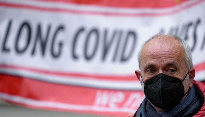 A man looks on as family members of people who died during the COVID-19 pandemic hold banners as they wait outside the UK COVID-19 inquiry, in London, Britain, on December 7, 2023. — Reuters