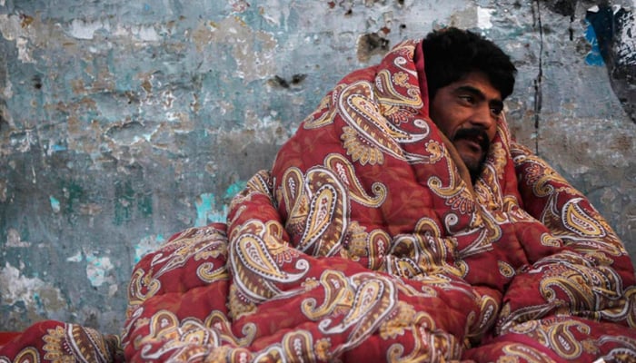 A man covers himself with a blanket to stay warm during winter in Karachi. — Reuters/File