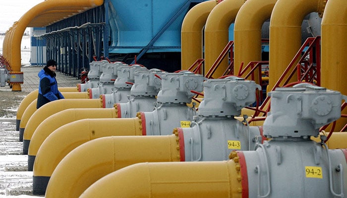 A gas worker walks between pipes in a compressor and distribution station of the Urengoy-Pomary-Uzhgorod gas pipeline, some 30 km (19 miles) from the south western Russian city of Kursk January 4, 2006. — Reuters