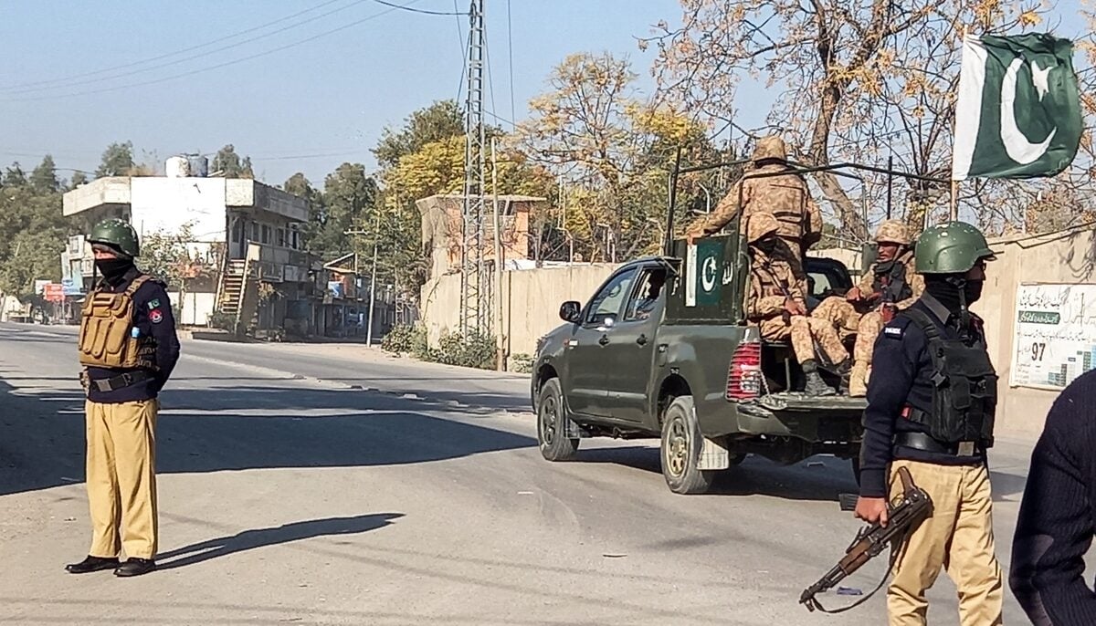 An Army vehicle patrols, past police officers stand guard along a road, near cantonment area in Bannu, Pakistan December 21, 2022. — AFP