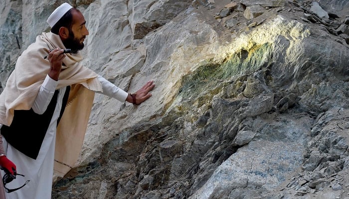 This photograph taken on January 18, 2025 shows an Afghan miner using a flashlight to inspect a rock, at a Nephrite mine in the mountains of Goshta district, Nangarhar province, Afghanistan. — AFP