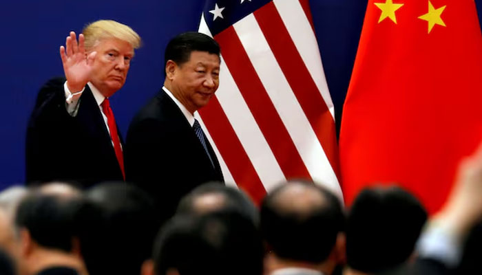 An undated image showing US President Donald Trump waiving as he walks alongside Chinese President Xi Jinping. — Reuters/File