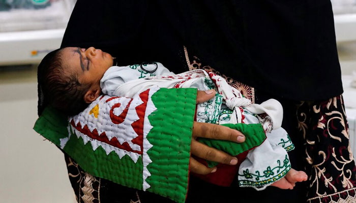 A mother carries her baby while waiting for medical assistance at a hospital in Sehwan, on September 7, 2022. — Reuters