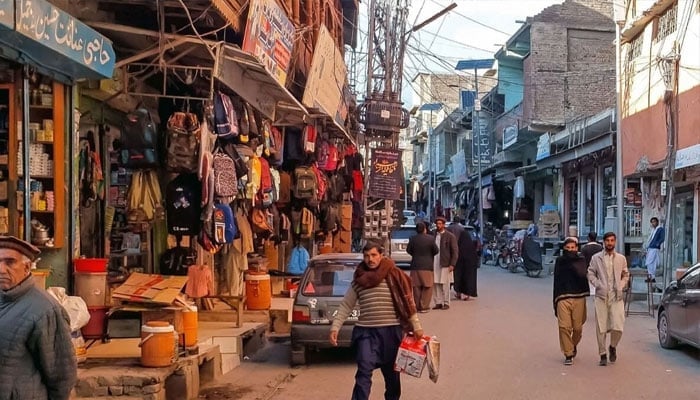 This photograph taken on December 3, 2024, shows local residents walking across a market reopened after clashes in Parachinar. — AFP