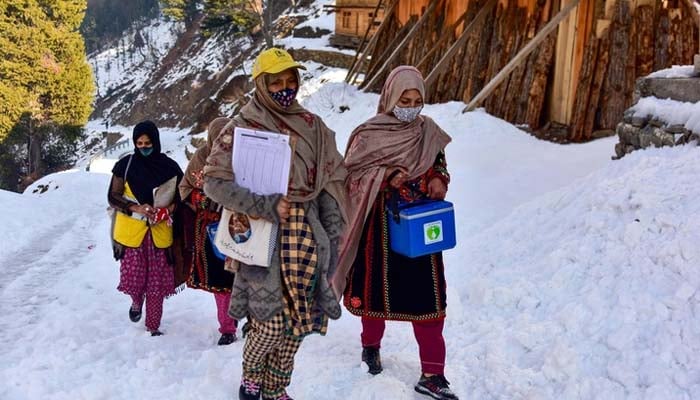 Health workers walk on snow during a polio vaccination drive in Azad Jammu and Kashmir, February 04, 2025. — AFP