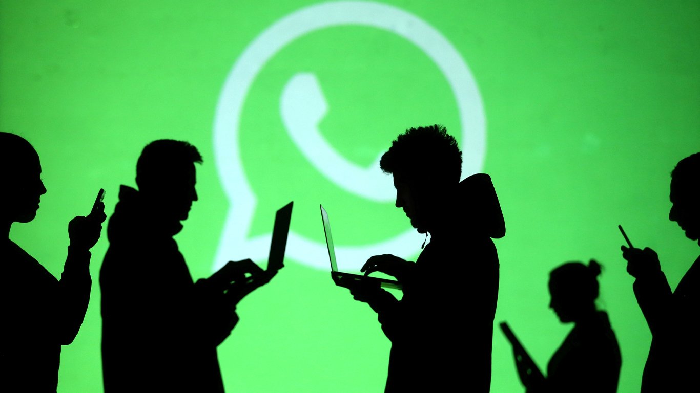 Silhouettes of laptop and mobile device users are seen next to a screen projection of Whatsapp logo in this picture illustration taken March 28, 2018. — Reuters