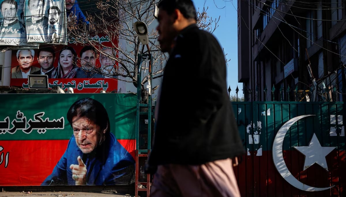 People walk past a banner with a picture of the former Prime Minister Imran Khan outside the party office of Pakistan Tehreek-e-Insaf (PTI), a day after the general election, in Lahore on February 9, 2024. — Reuters