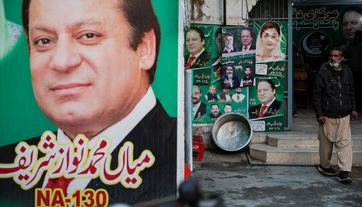 A man stands near the banner and campaign posters of Pakistans former Prime Minister Nawaz Sharif ahead of the general elections, in Lahore on February 5, 2024. — Reuters