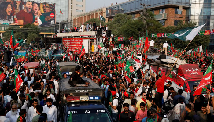 Former prime minister Imran Khan waves the national flag on a truck to his supporters as he attends a rally in Lahore, on October 28, 2022. — Reuters