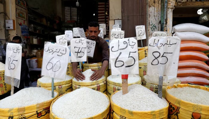 A vendor arranges different types of rice, with their prices displayed, at his shop in a wholesale market in Karachi. — Reuters