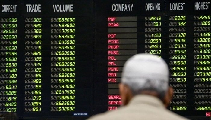 A trader stands beneath an electronic board displaying share prices at the PSX. — INP/File