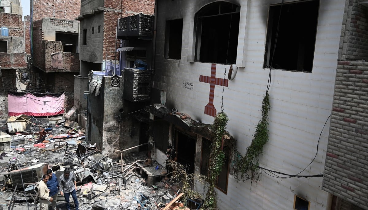 Men stand amid debris outside the torched Saint John Church in Jaranwala on the outskirts of Faisalabad on August 17, 2023. — AFP