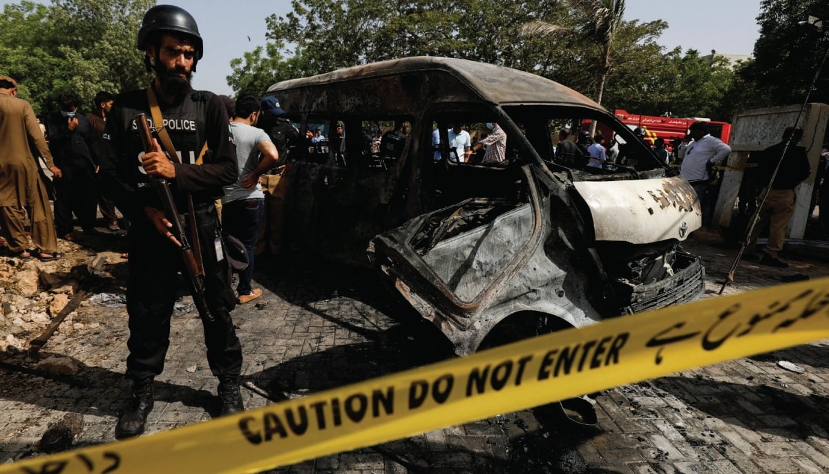 A police officer stands guard near a passenger van, cordoned after a blast at the entrance of the Confucius Institute University of Karachi on April 26, 2022. — Reuters