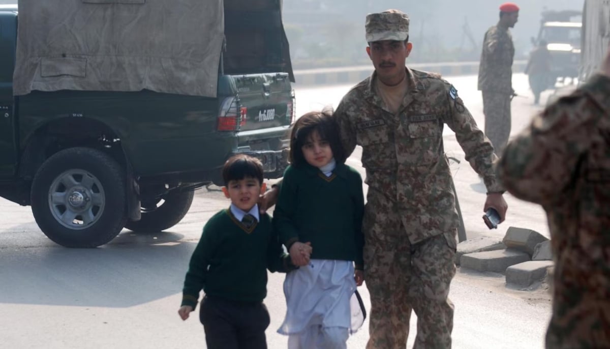 A soldier escorts schoolchildren from the Army Public School that is under attack by Taliban gunmen in Peshawar, December 16, 2014. — Reuters