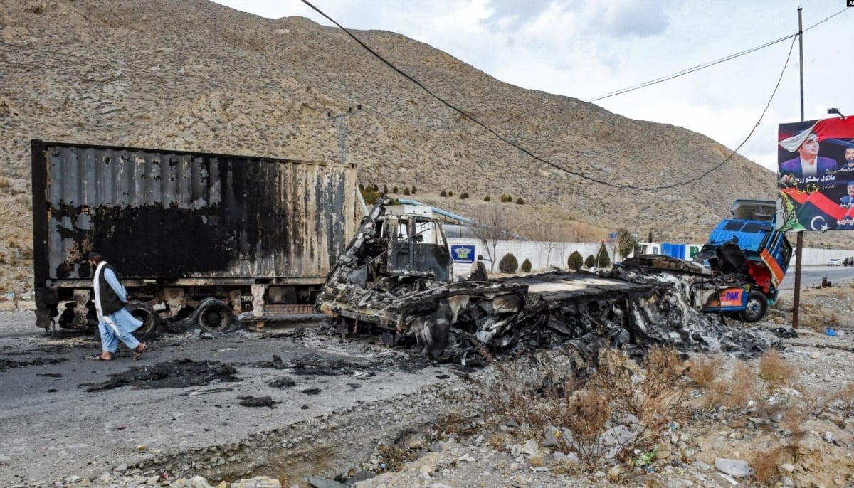 A man walks past charred truck containers torched by the BLA in the central Bolan district in Balochistan on January 30, 2024. — AFP