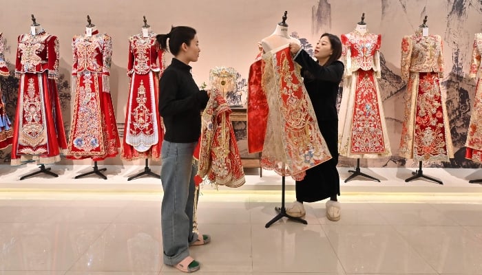 A woman checks her wedding dress at a bridal shop in Luliang, northern Chinas Shanxi province on February 11, 2025. — AFP