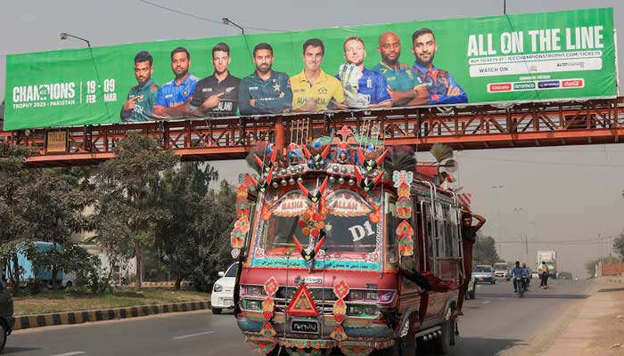 A decorated van drives past under a pedestrian bridge with an advertisment banner, ahead of the ICC Champions Trophy 2025 tournament, in Karachi on February 13, 2025. — Reuters