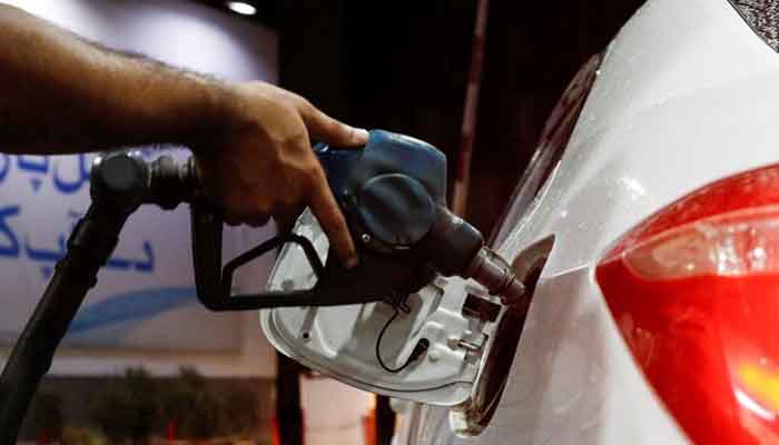 A worker has a fuel nozzle to fill the fuel in a car, after the government announced the increase in petrol and diesel prices at the Karachi, Pakistan, September 16, 2023.