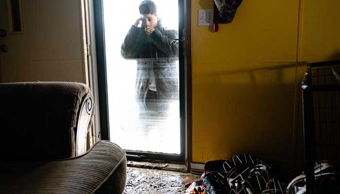 A child reacts as he looks into his flooded trailer for the first time, where waters reached around 7 feet high, at Ramsey Mobile Home Park following rain storms that caused flooding on February 17, 2025 in Pikeville, Kentucky. — AFP