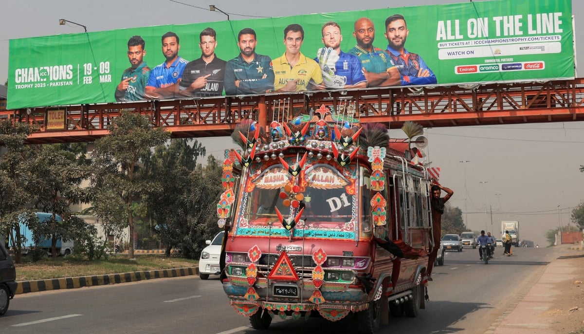 A decorated van drives past under a pedestrian bridge with an advertisement banner, ahead of the ICC Champions Trophy 2025 tournament, in Karachi on February 13, 2025. — Reuters