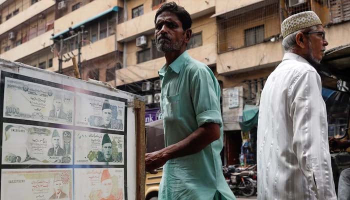 People walk past a sidewalk money exchange showcase, which is decorated with pictures of currency notes, in Karachi, Pakistan September 12, 2023. — Reuters