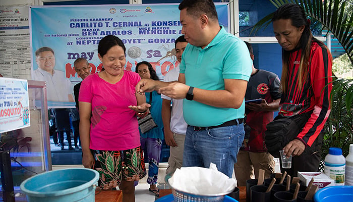 Village chief Carlito Cernal (C) pays a resident who handed over a plastic container with mosquitos at the start of peso for a mosquito programme to eradicate dengue in Manila on February 19, 2025. — AFP