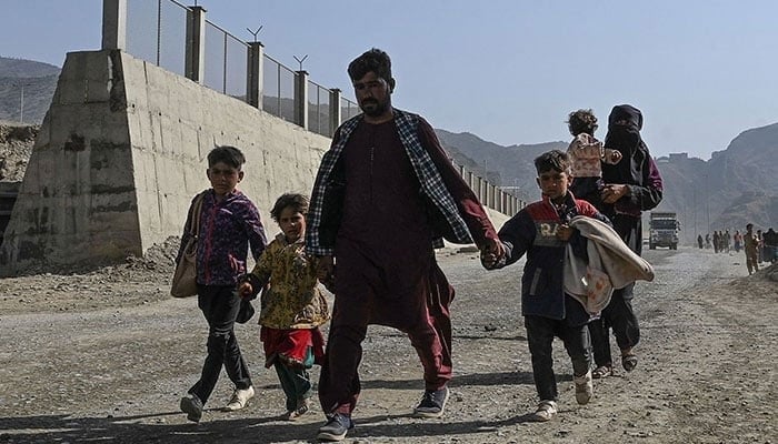 An Afghan refugee family arrives on foot to cross the Pakistan-Afghanistan Torkham border on November 2, 2023. — AFP