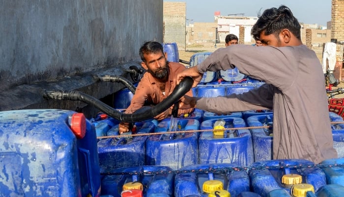 Vendors fill cans with drinking water for sale, from a private water supply plant in Jacobabadon February 18, 2025. — AFP