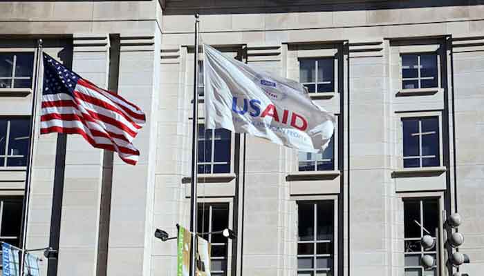 An American flag and USAID flag fly outside the USAID building in Washington, DC, US, February 1, 2025. — Reuters