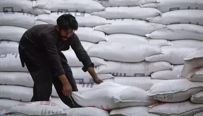 A labourer unloads sacks of sugar from a supply truck at the main wholesale market in Karachi. — Reuters