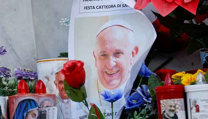 A photo of Pope Francis is placed next to candles and flowers at the base of the statue of the late Pope John Paul II outside the Gemelli Hospital where Pope Francis is admitted for treatment, in Rome, Italy, February 23, 2025. — Reuters