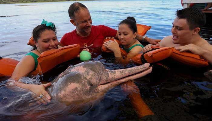 Physiotherapist Igor Simoes Andrade and young people with disabilities swim with pink dolphins (Inia geoffrensis) on the Rio Negro river in Iranduba, Amazonas state, Brazil, on February 20, 2025. — AFP