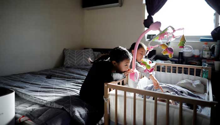 Girls take care of their baby brother before leaving for school, at their home in Seoul, South Korea, December 19, 2018. — Reuters