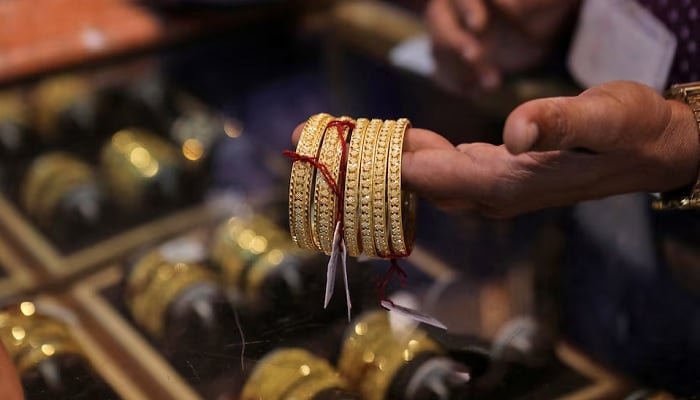 A salesperson shows gold bangles to a customer at a jewellery showroom, in Mumbai, India, October 22, 2022. — Reuters